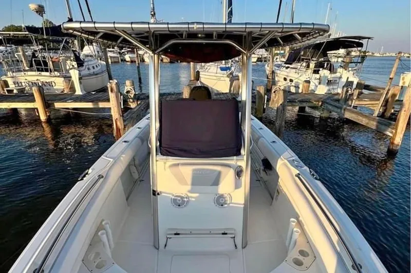 Slide: The Image of 2013 Boston Whaler 220 Outrage boat docked at a marina, surrounded by watercraft. - 6