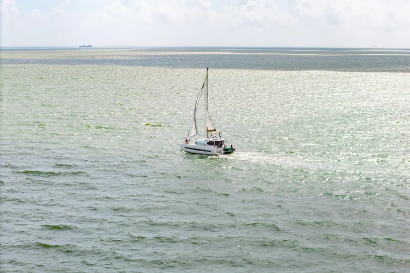 Slide: The Image of Sailboat Bali 4.1 cruising on green ocean waters under cloudy skies, 2019 model. - 78