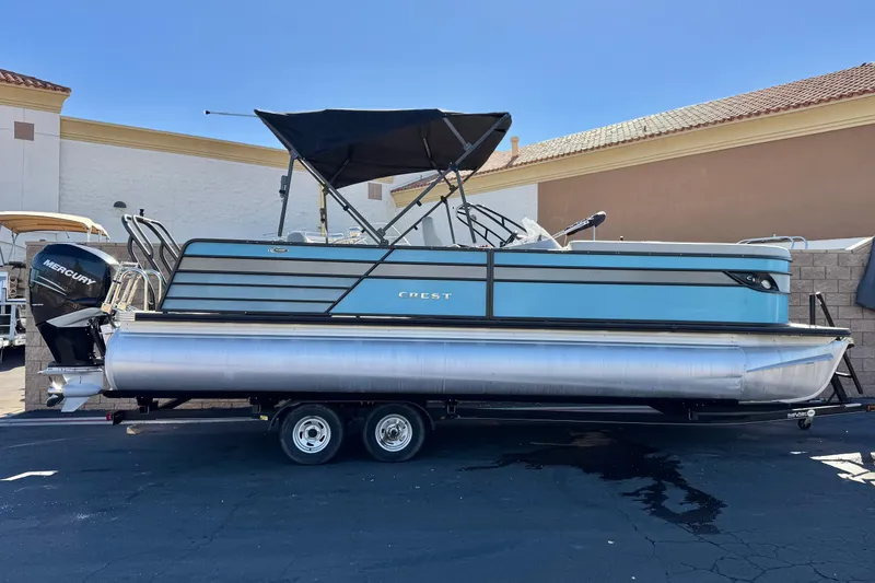 The Image of 2021 Crest Classic Platinum 240 SLC pontoon boat on trailer, featuring Mercury outboard motor. - 0