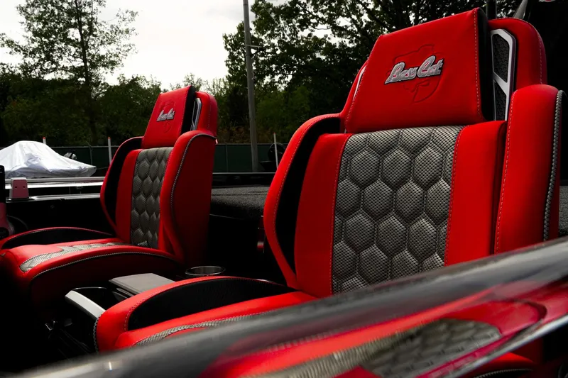Slide: The Image of 2026 Bass Cat Cougar FTD seats, red and gray design, outdoor setting. - 10