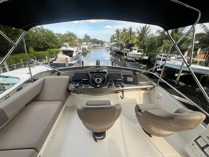 Slide: The Image of 2017 Marquis 500 Sport Yacht helm with dual seats, docked in a scenic marina. - 15