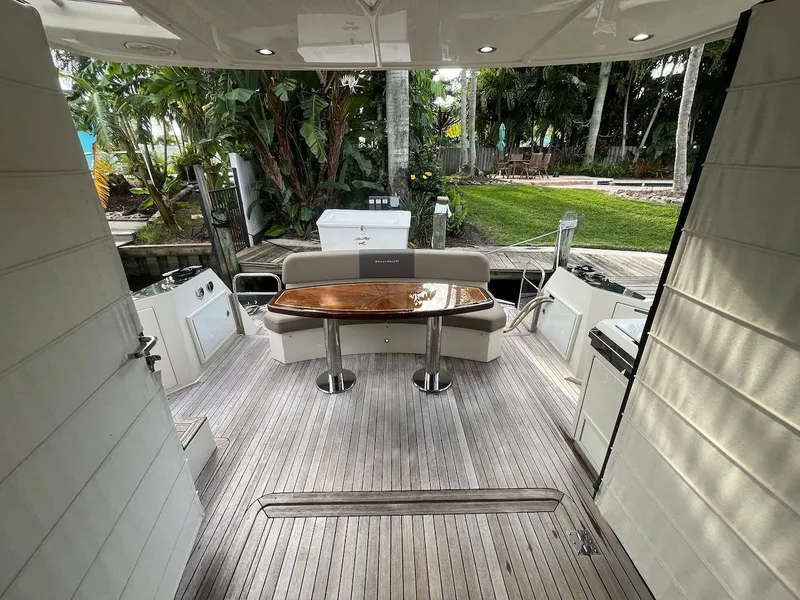 Slide: The Image of 2017 Marquis 500 Sport Yacht deck with wooden table and seating. - 25