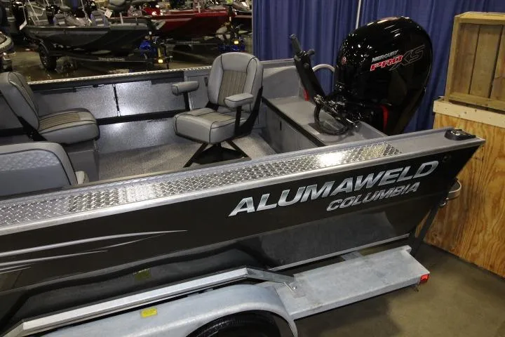 Slide: The Image of 2026 Alumaweld Columbia 21 boat interior with seating and motor, displayed at a boat show. - 2
