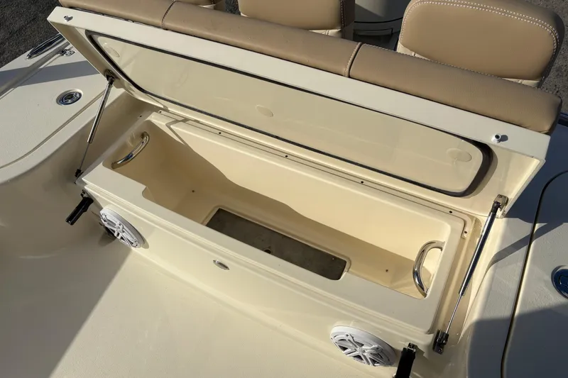 Slide: The Image of 2026 Scout 231 XSB boat storage compartment with open lid and beige seating. - 11