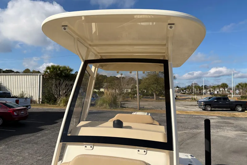 Slide: The Image of 2026 Scout 231 XSB boat with T-top and windshield, parked outdoors under blue sky. - 25
