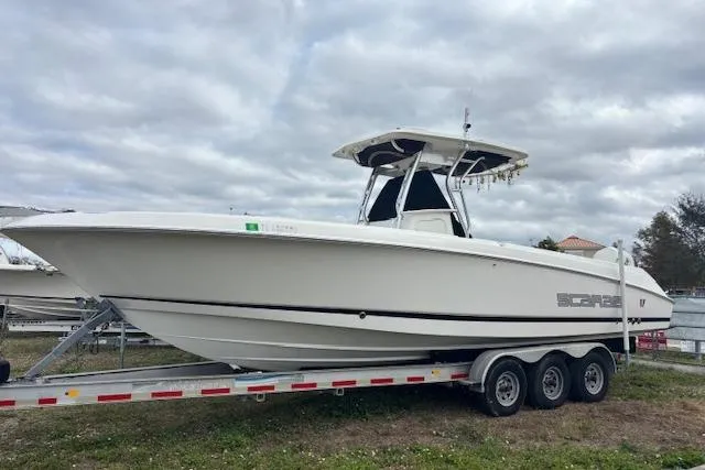 The Image of 2013 Wellcraft 30 Scarab Sport boat on a trailer under cloudy skies. - 0