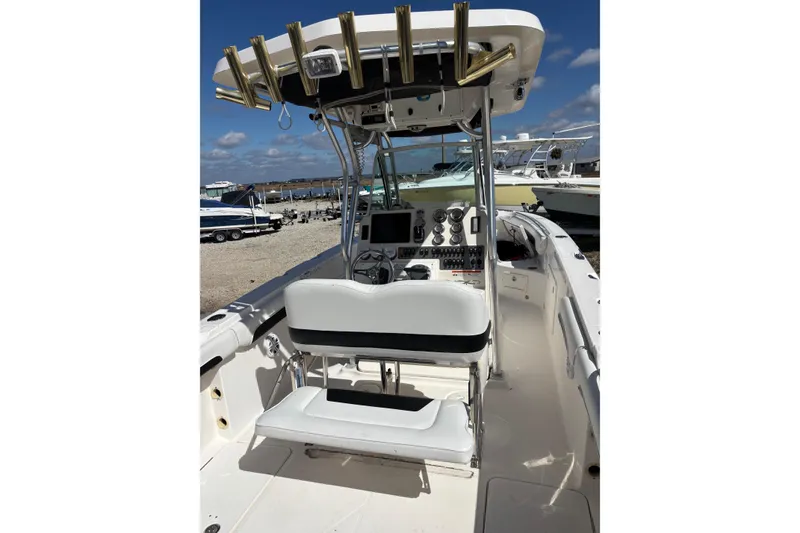 Slide: The Image of 2013 Wellcraft 30 Scarab Sport boat interior with helm and seating, docked under clear skies. - 6