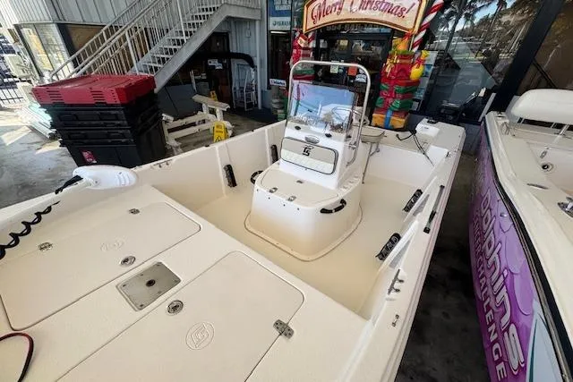 Slide: The Image of 2023 Carolina Skiff 162 JLS boat interior with console and seating, displayed in a showroom. - 13