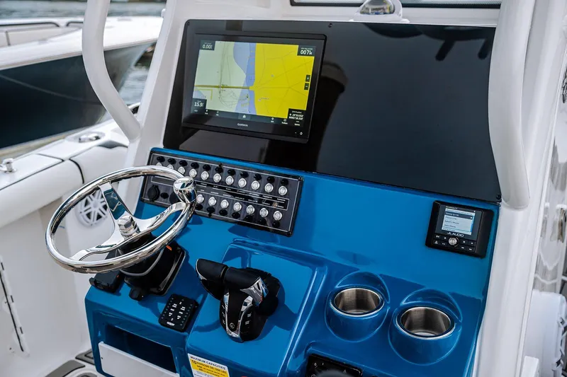 Slide: The Image of 2026 Tidewater 256 LXF boat on trailer, parked outside a marina under a clear blue sky. - 22