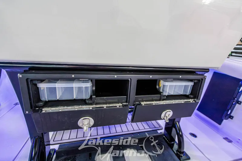 Slide: The Image of 2026 Tidewater 256 LXF boat storage compartments with secure locks and organized tackle boxes. - 52