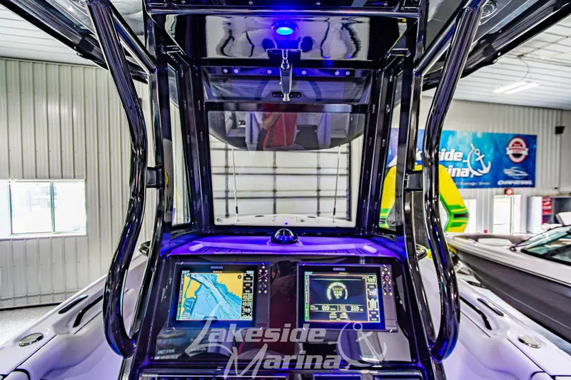 Slide: The Image of 2026 Tidewater 256 LXF boat dashboard with navigation screens in a marina showroom. - 69