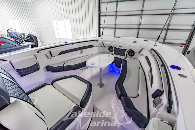 Slide: The Image of 2026 Tidewater 256 LXF boat interior with seating and table in a marina setting. - 95