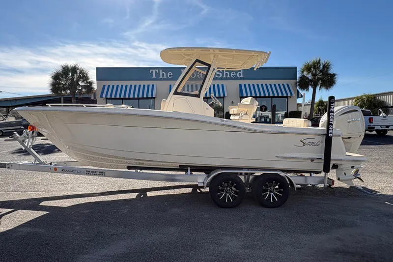 Slide: The Image of 2026 Scout 240 XSF boat with Yamaha engine on trailer, parked outside a building. - 1