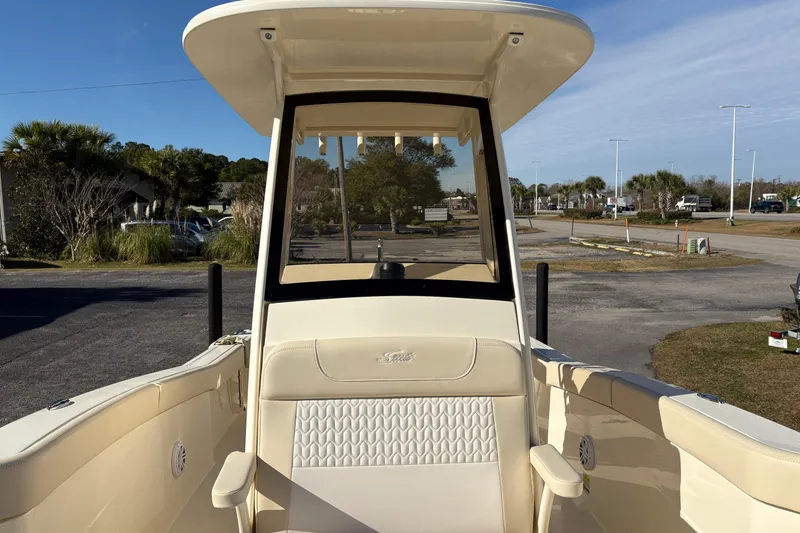 Slide: The Image of 2026 Scout 240 XSF boat interior with seating and console, parked outdoors. - 28