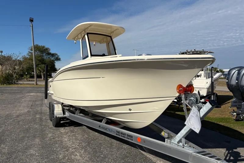 Slide: The Image of 2026 Scout 240 XSF boat on trailer, parked outdoors under clear sky. - 6