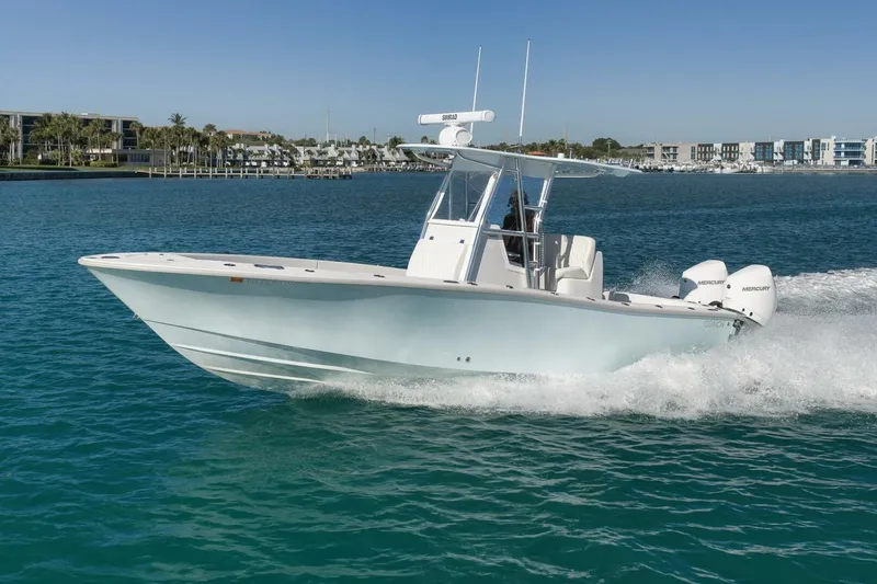 Slide: The Image of 2025 Conch 27 boat cruising on clear blue water near a coastal city. - 10