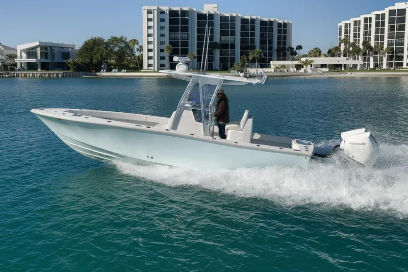 Slide: The Image of 2025 Conch 27 boat cruising on clear blue water near modern buildings. - 11