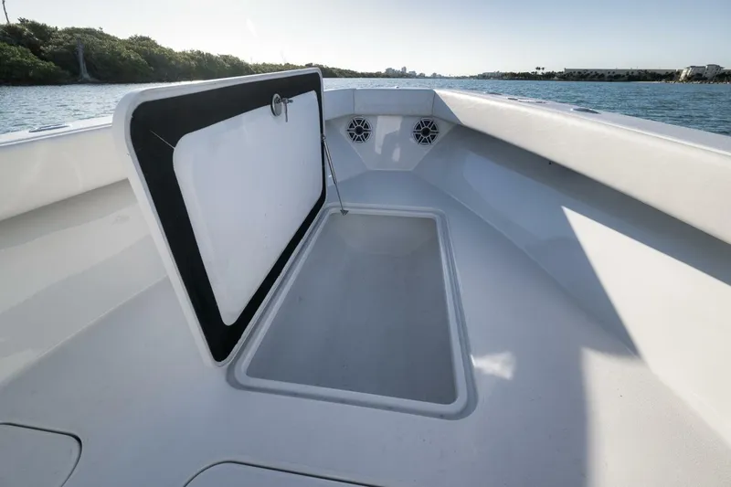 Slide: The Image of 2025 Conch 27 boat interior with open storage compartment, docked near lush shoreline. - 19
