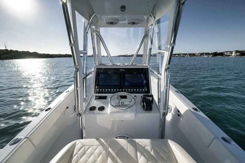 Slide: The Image of 2025 Conch 27 boat interior with steering console, on calm water under clear sky. - 26