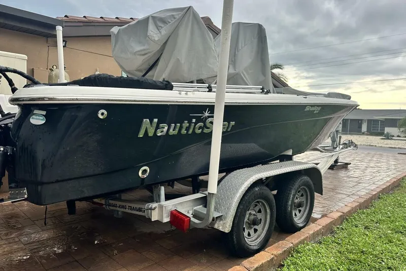 Slide: The Image of 2020 NauticStar 2140 Sport Shallow Bay boat on trailer, parked in driveway. - 2