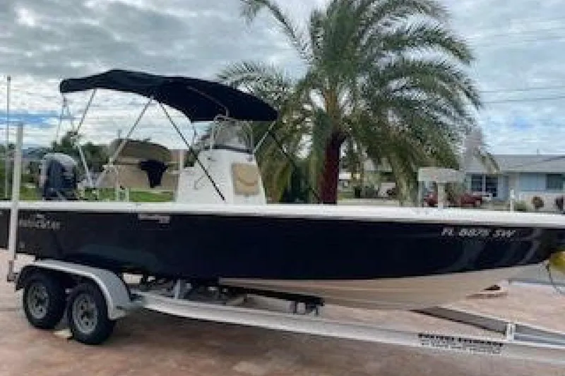 Slide: The Image of 2020 NauticStar 2140 Sport Shallow Bay boat on trailer, palm tree background. - 4