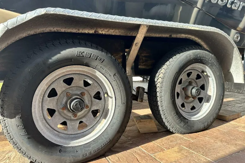 Slide: The Image of Trailer wheels of a 2020 NauticStar 2140 Sport Shallow Bay boat on wooden blocks. - 49