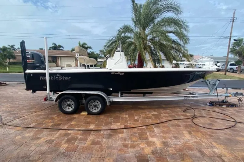 Slide: The Image of 2020 NauticStar 2140 Sport Shallow Bay boat on trailer, parked on brick driveway. - 55