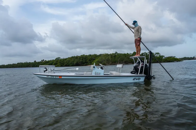 Slide: The Image of 2020 East Cape 18 EVO boat with person poling in calm waters, cloudy sky backdrop. - 30