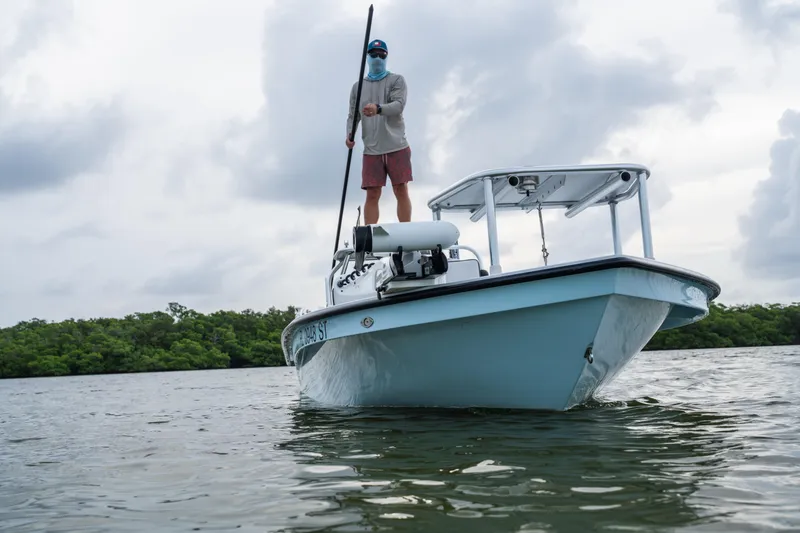 Slide: The Image of 2020 East Cape 18 EVO boat on water with person standing, cloudy sky background. - 31