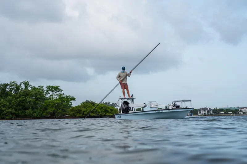 Slide: The Image of Man navigating East Cape 18 EVO boat with pole in calm waters, 2020 model. - 32