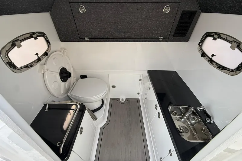Slide: The Image of 2026 Monterey Elite 27 OB boat interior with toilet, sink, and storage cabinets. - 26