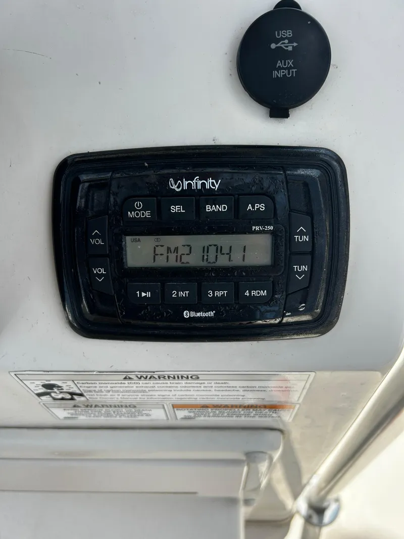 Slide: The Image of Infinity stereo system on a 2015 Carolina Skiff 21 Ultra Elite boat, displaying FM 104.1. - 14