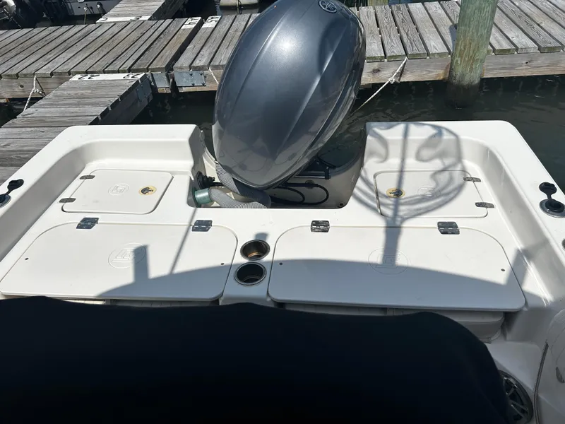 Slide: The Image of 2015 Carolina Skiff 21 Ultra Elite boat at dock, featuring engine and storage compartments. - 21