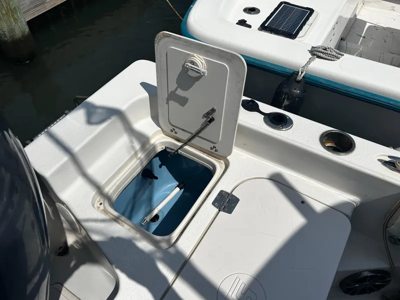 Slide: The Image of Open storage compartment on 2015 Carolina Skiff 21 Ultra Elite boat, docked by water. - 23