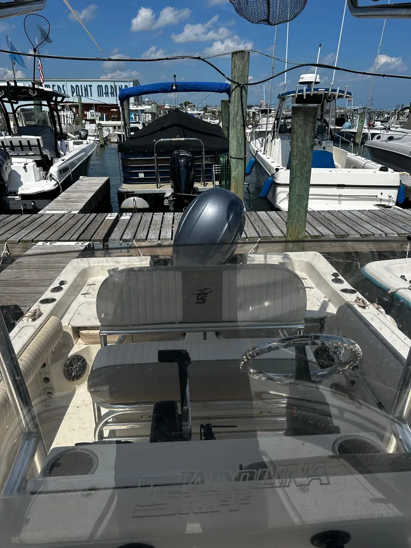Slide: The Image of 2015 Carolina Skiff 21 Ultra Elite boat docked at a marina under a clear blue sky. - 25