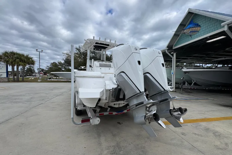 Slide: The Image of 2026 Caymas 291 boat with dual outboard engines, parked outdoors under cloudy skies. - 23