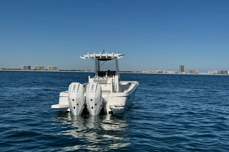 Slide: The Image of 2026 Caymas 291 boat with dual engines on open water, city skyline in background. - 4
