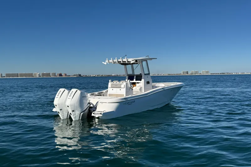Slide: The Image of 2026 Caymas 291 boat with dual engines on calm water, city skyline in background. - 6