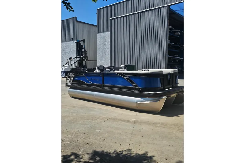 Slide: The Image of 2022 Godfrey Monaco 235 SFL pontoon boat with blue and black design on a sunny day. - 2