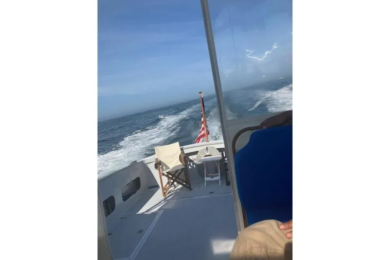 Slide: The Image of 1978 Dyer 40 Express Cruiser on open sea, featuring deck chairs and American flag. - 15