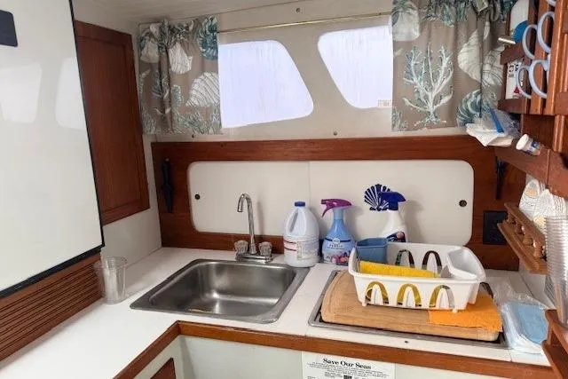 Slide: The Image of 1978 Dyer 40 Custom Express Cruiser kitchen with sink, cleaning supplies, and dish rack. - 39