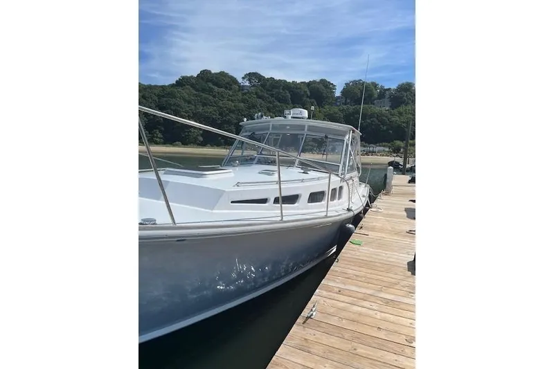 Slide: The Image of 1978 Dyer 40 Express Cruiser docked by a wooden pier, under a clear sky. - 4