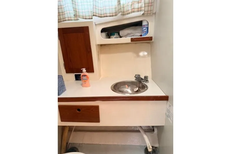 Slide: The Image of 1978 Dyer 40 Custom Express Cruiser bathroom with sink, wooden cabinets, and toiletries. - 54