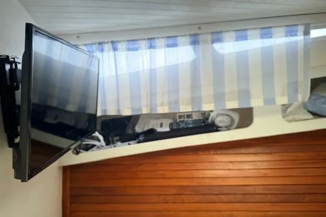 Slide: The Image of 1978 Dyer 40 Custom Express Cruiser interior with mounted TV and striped curtains. - 61