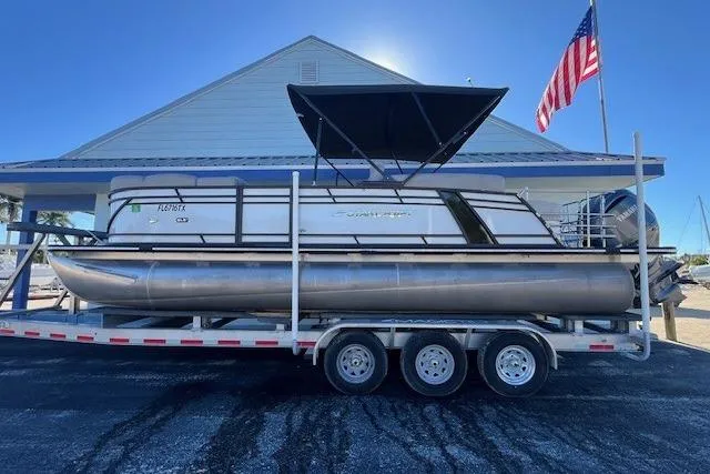 The Image of 2024 Starcraft SLS 3 Q DH pontoon boat on trailer, American flag in background. - 1