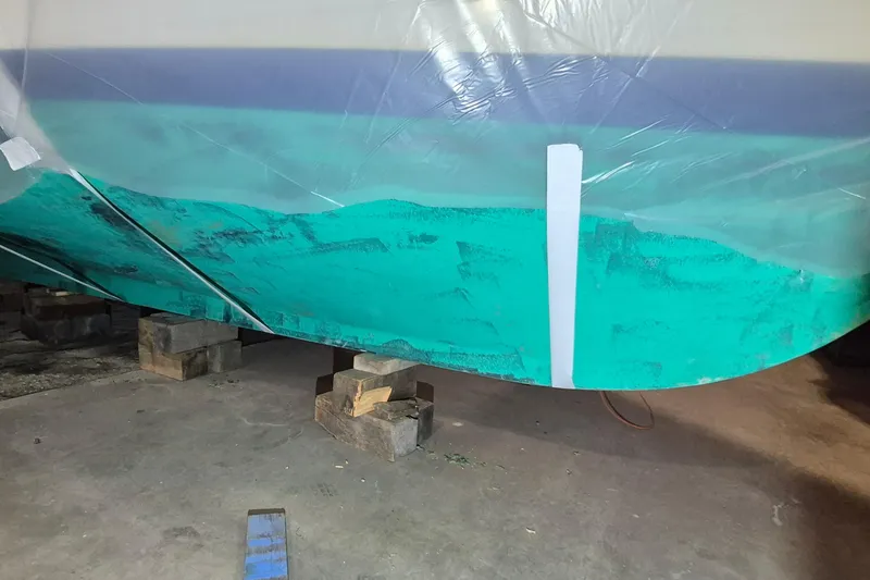 Slide: The Image of 1985 Grand Banks 42 Classic boat hull under maintenance, supported by wooden blocks. - 114