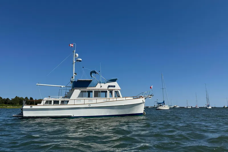 Slide: The Image of 1985 Grand Banks 42 Classic yacht on calm water under clear blue sky. - 2