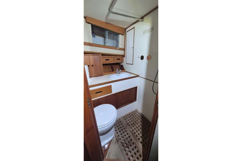 Slide: The Image of 1985 Grand Banks 42 Classic yacht bathroom with wooden cabinetry and white fixtures. - 22