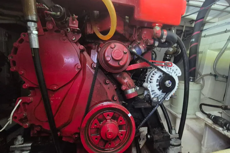 Slide: The Image of Engine compartment of a 1985 Grand Banks 42 Classic, featuring a red engine and belt system. - 43