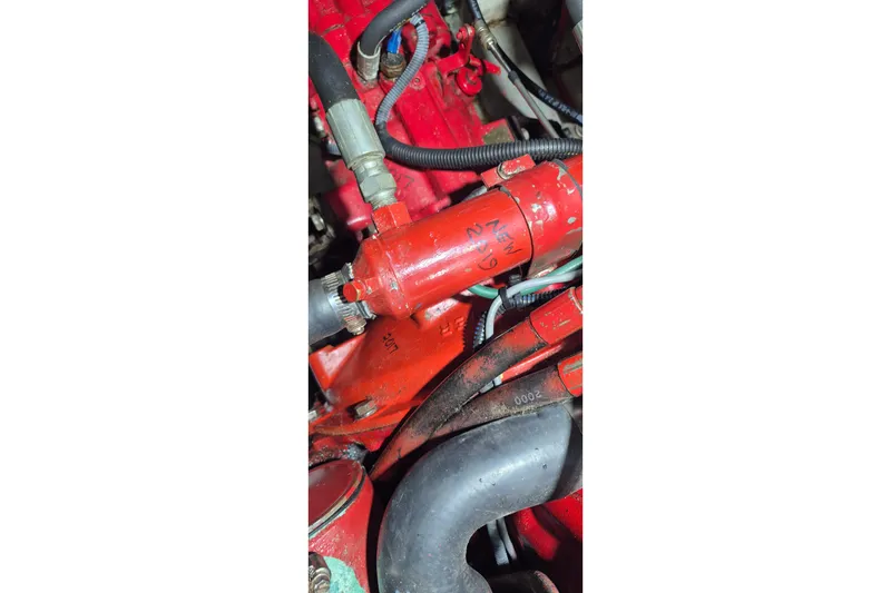 Slide: The Image of Engine components of a 1985 Grand Banks 42 Classic, featuring red hoses and connectors. - 57